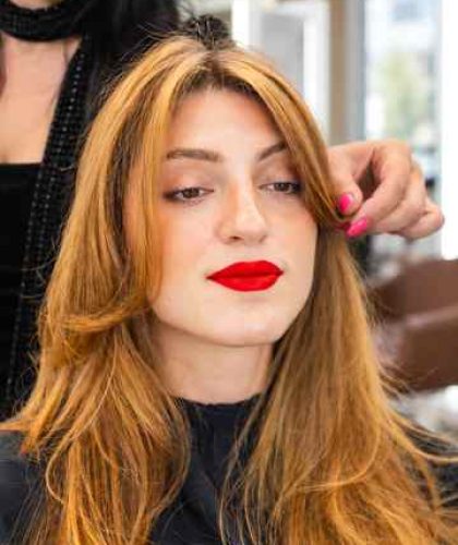 Stylist cutting layers into a woman's hair at a Los Angeles salon